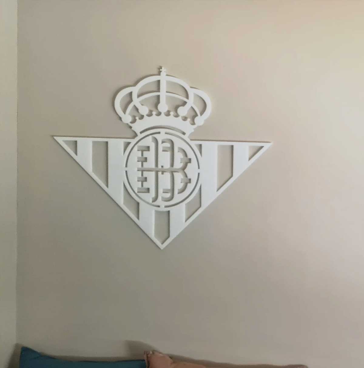 Escudos de fútbol en blanco para pared: escudo de Real Betis en blanco colocado en una pared interior, con un encuadre sencillo y directo